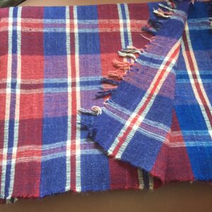 Hand woven red white and blue plaid blanket. This piece was woven in three strips that were then sewn together.